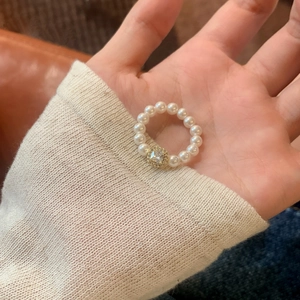 Elegant pearl ring with a square center zircon crystal shown on hand with a warm knit sleeve