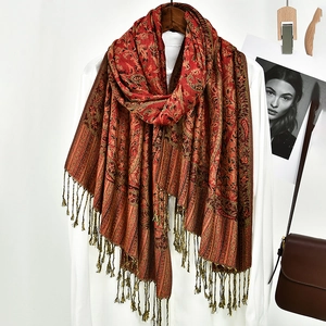 Detail view of ethnic paisley shawl with decorative tassels on a white shirt