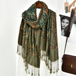 Detail of vintage paisley shawl with fringe hanging on a white shirt with leather bag
