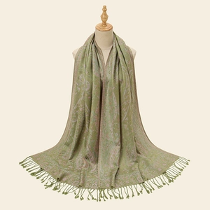 Close-up of ethnic paisley embroidery and long fringe details on green pashmina shawl