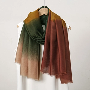 Detail of soft gradient scarf with fringe edges in forest green and caramel tones