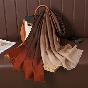 Gradient brown cotton linen scarf with frayed edges draped over a luxury leather handbag