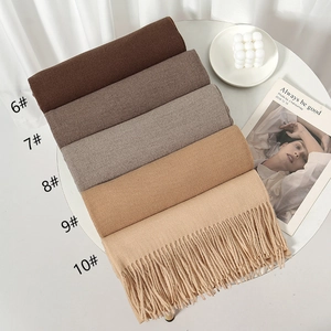 Detail view of five earth-toned cashmere-like scarves with fringe in a flat lay setup