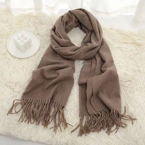 Detailed view of the thick fringe and soft texture on a dark khaki winter scarf