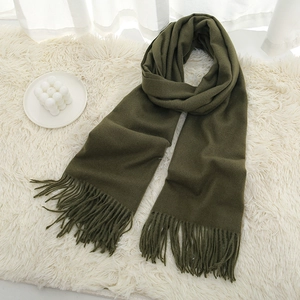 Thick army green cashmere scarf with fringe tassels on white plush carpet background
