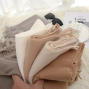 Détail rapproché de diverses écharpes unies en imitation cachemire avec de doux pompons.
