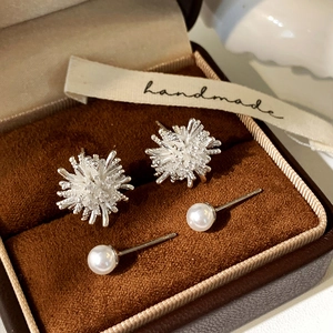 Macro shot of silver fireworks studs and white pearl earrings in brown velvet gift box