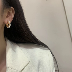 Boucles d'oreilles perles dorées en forme de C portées par un mannequin en veste tweed