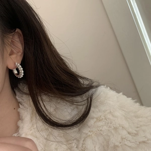 Gros plan de boucles d'oreilles argentées en C avec perles blanches portées par un mannequin