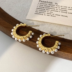 Gros plan de boucles d'oreilles créoles C en perles dorées avec relief vintage sur toile