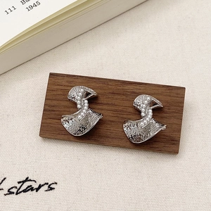 Vue macro des boucles d'oreilles en argent martelé avec une rangée de perles blanches