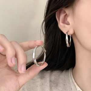 Minimalist silver irregular twisted hoop earrings with a polished metallic finish on a model