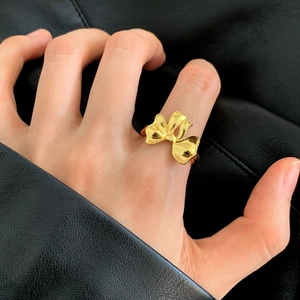 Elegante anello aperto a forma di fiocco dorato con bordi strutturati sull'indice
