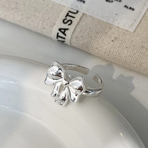 Dettaglio macro di anello a fiocco argento con bordi perlati su piatto bianco