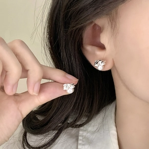 Elegant bow knot pearl stud earrings made of silver metal for women shown on ear