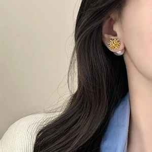 Elegant gold starburst pearl double-sided stud earrings worn by a model in a side view
