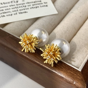 Detail of luxury fireworks gold earrings with large white pearls and sparkling zircon tips