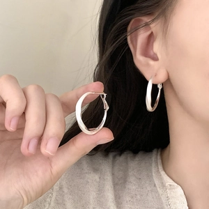 Silver twisted hoop earrings with a mirror finish shown on a model for a minimalist look