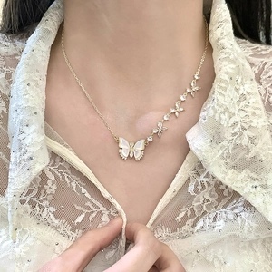 Collier papillon doré élégant avec ailes en nacre et diamants porté par un mannequin