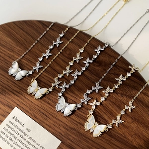 Détail de colliers papillon en nacre avec zircons sur un support en bois sombre