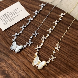 Détail de colliers papillon élégants en or et argent avec ailes en nacre sur bois