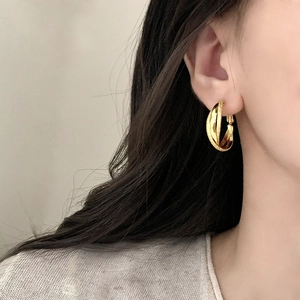 Minimalist geometric gold layered hoop earrings with matte textured finish worn on ear