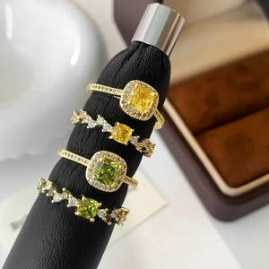 Elegant 4-piece gold ring set with green and yellow square stones on black ring stand