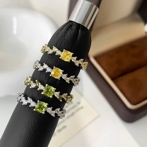 Macro detail of square-cut yellow and green gemstone rings with wavy zirconia bands