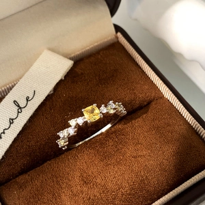 Detail view of a silver ring with square yellow gemstone and pave-set zircons on velvet