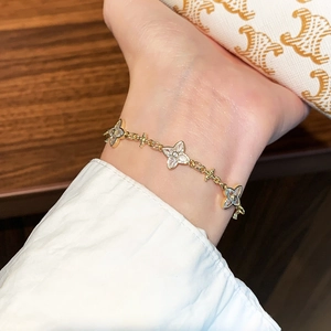 Detail of gold four-leaf clover bracelet with zircon charms on a female wrist