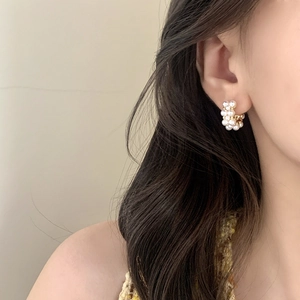 Elegant C-shaped cluster pearl earrings with gold base shown on a model for daily wear