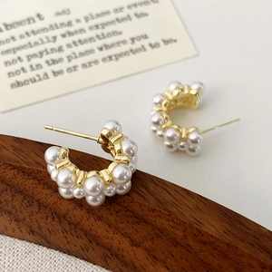 Macro shot of elegant C-shaped pearl earrings with gold plating and S925 silver studs