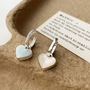 Détail de boucles d'oreilles cœur asymétriques avec texture marbre bleu et nacre