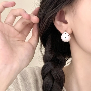 Minimalistische rosa und schwarze gepunktete Creolen, die von einem Model getragen werden
