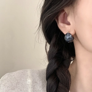 Schwarze Marmor-Ohrringe mit weißen Punkten und Golddetails an einem Modell getragen