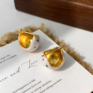 Detailansicht goldener Creolen mit cremefarbener Emaille und schwarzen Sprenkelmustern