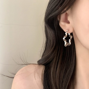 Minimalist silver geometric star earrings in a cube-shaped design worn by a model