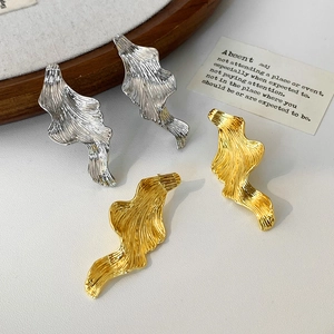 Irregular vintage metal earrings in gold and silver finish with lava ripple texture