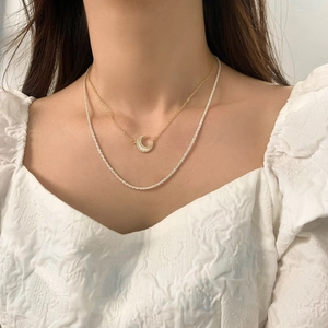 Minimalist layered necklace featuring a gold moon pendant with pearl and sparkling chain