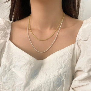 Minimalist gold and silver layered chain necklaces showing a shimmering link texture on model