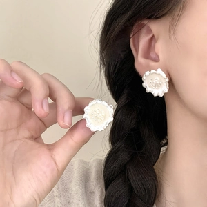 Élégantes boucles d'oreilles fleurs crème mat avec cœur perlé sur un mannequin