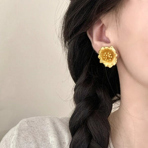 Élégantes boucles d'oreilles fleurs en or mat pour femmes portées par un mannequin de profil