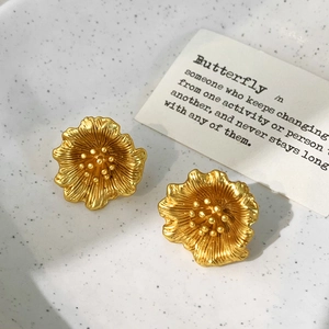 Détails des boucles d'oreilles fleur dorées avec texture métal brossé et centre perlé