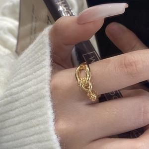 Minimalist knot design gold chain ring shown on finger with a warm lifestyle background
