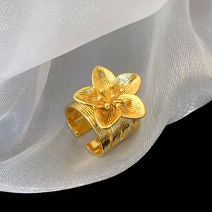 Macro shot of gold floral ring with layered five-petal design and textured wide band