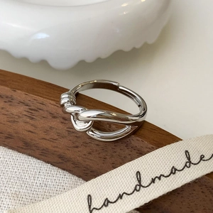 Macro detail of silver knot ring with handmade ribbon on a dark wooden surface