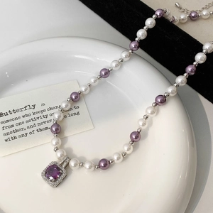 Détail du collier de perles avec pendentif gemme violette sur un plateau en céramique
