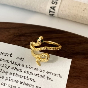 Macro view of gold snake ring featuring green zircon eyes and detailed scale texture