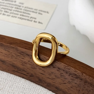 Macro shot of minimalist gold hollow oval ring featuring high-polish finish on wood