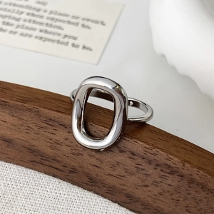 Macro shot of silver hollow oval ring with polished mirror finish on wooden display